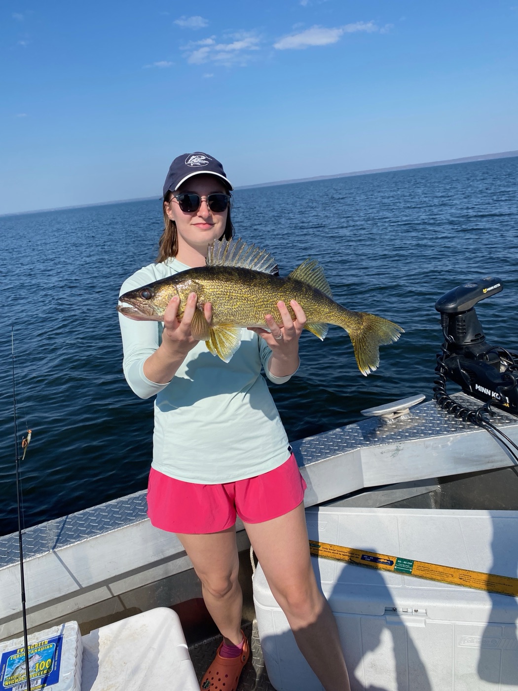 Guest holding a walleye on the boat on Lake Nipissing wearing a Lake Nipissing Outfitters cap