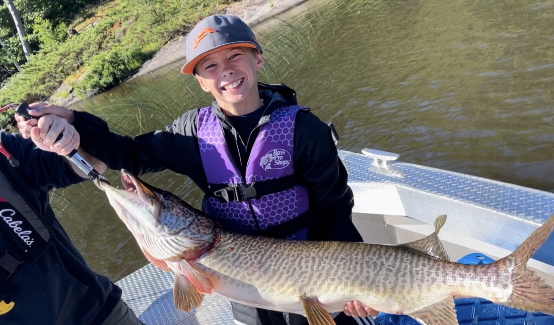 Young angler holding a large musky caught on a guided fishing trip